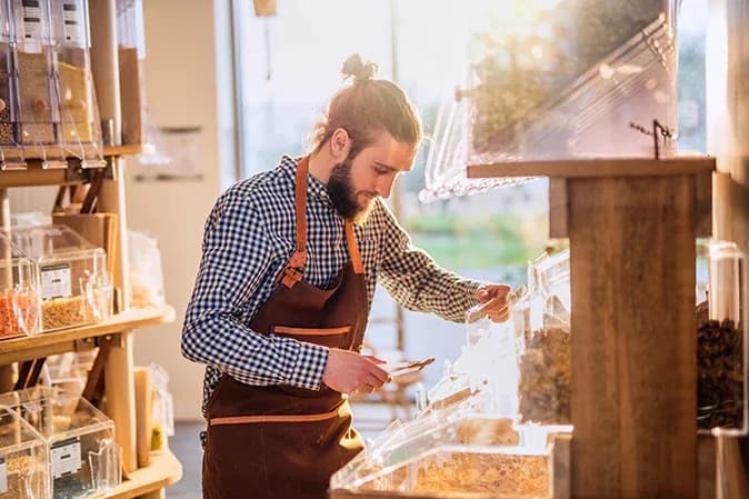homme en tablier servant des produits en vrac dans un magasin lumineux et accueillant