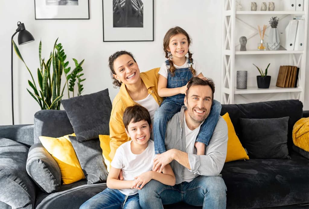 famille souriante posant sur un canapé dans un salon lumineux et moderne