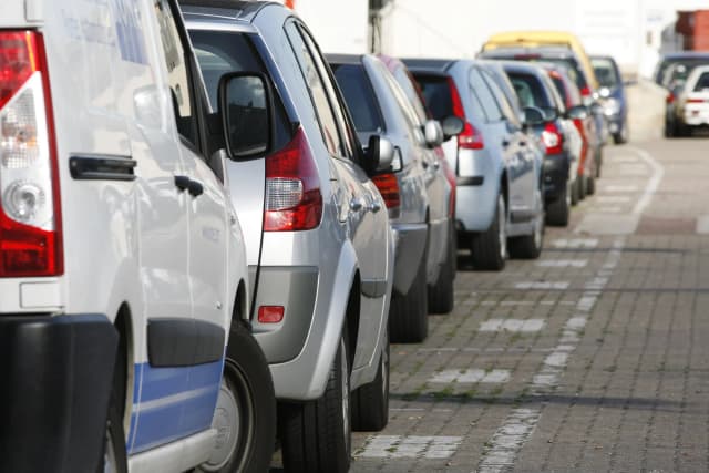 voitures garées sur une rue avec des pavés et un bâtiment en arrière-plan