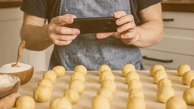 mains qui photographient des boules de pâte disposées sur le plan de travail