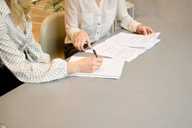 deux personnes discutent et examinent des documents sur une table en milieu professionnel