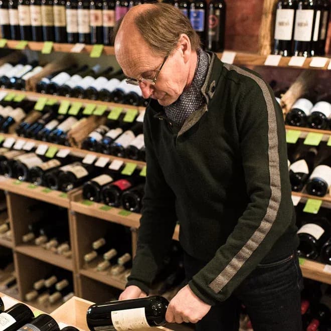 caviste vérifiant l'étiquette d'une bouteille dans une cave à vins