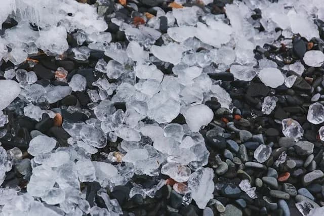 morceaux de glace sur un sol de galets noirs et gris