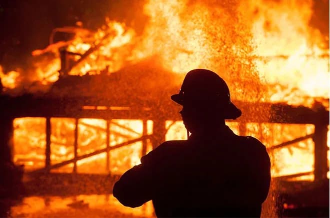 silhouette d'un pompier face à un bâtiment en flammes